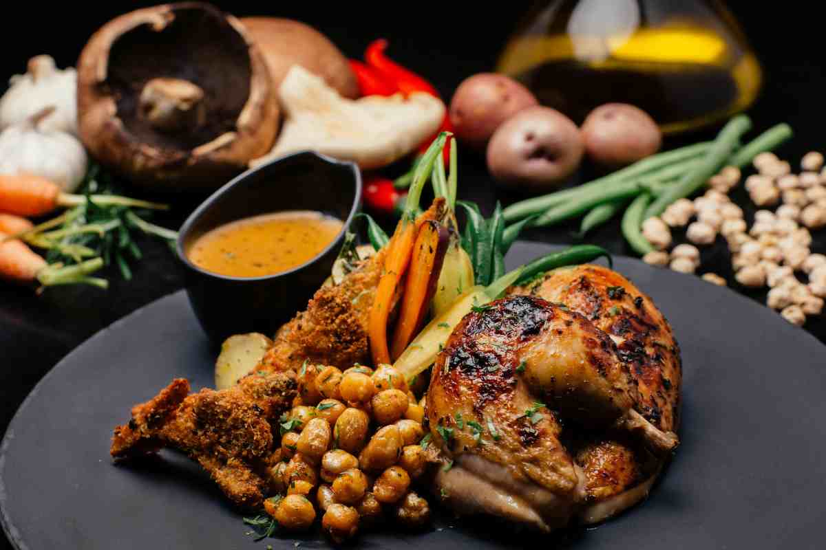 piatto con pollo arrosto tagliato, contorno e salsa