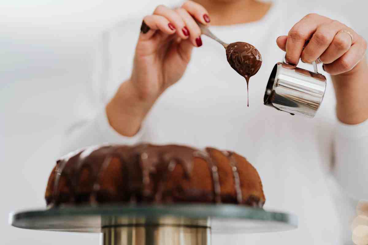 pasticcere che fa colare la glassa sul dolce con un pentolino