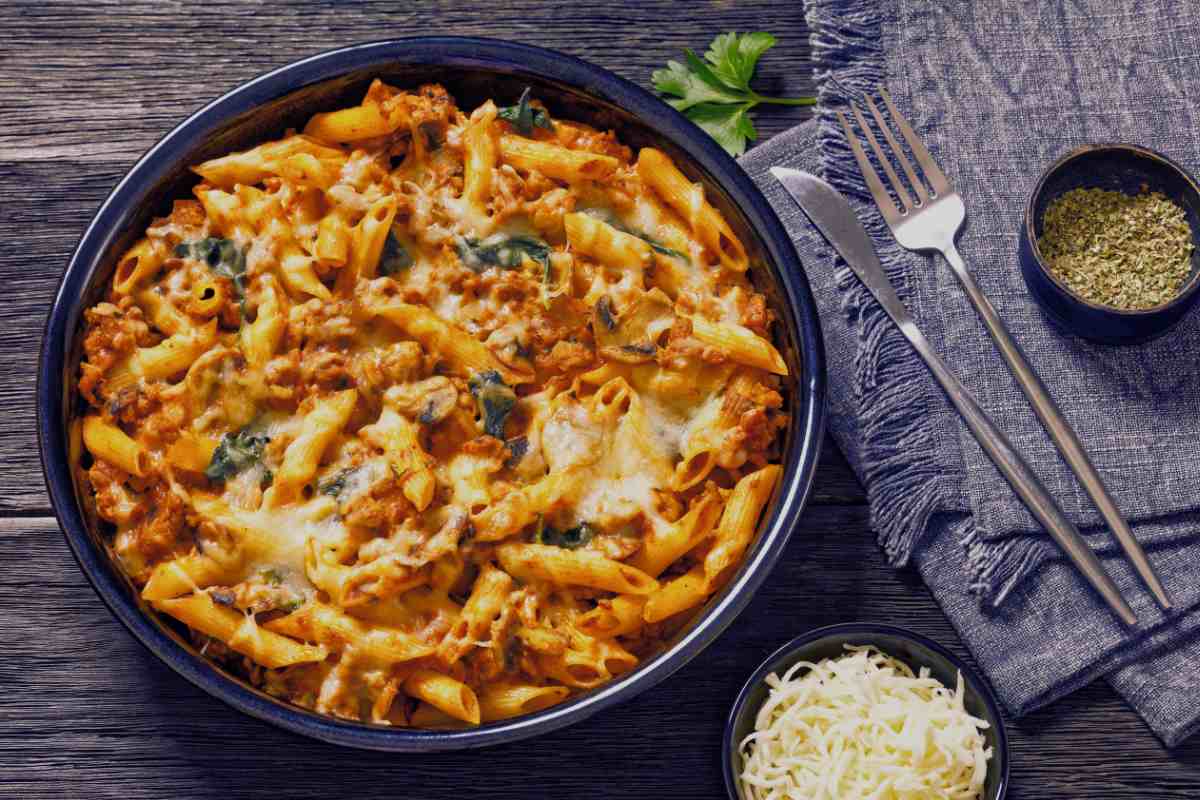 piatto tondo con pasta al forno con accanto il formaggio