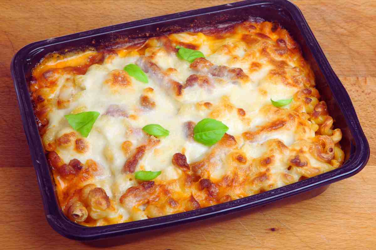 teglia di pasta al forno con foglioline di basilico sopra un tavolo di legno